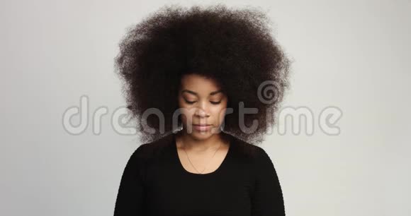 有着一头巨大的非洲头发的贝维特黑人女人笑着抚摸着她的头发视频的预览图