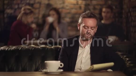 男人在笔记本上发短信在咖啡馆喝茶视频的预览图