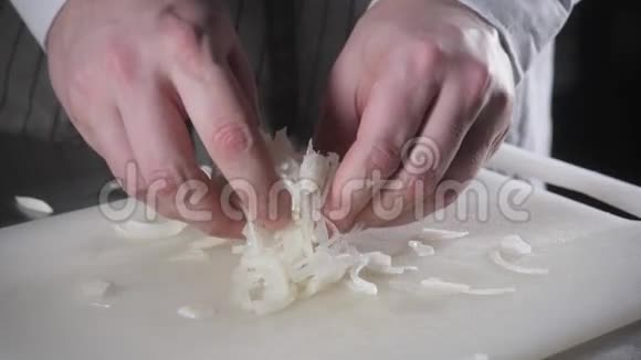 用刀切新鲜蔬菜的手特写年轻的厨师在白色的切割板特写上切洋葱烹饪视频的预览图