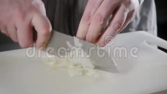 用刀切新鲜蔬菜的手特写年轻的厨师在白色的切割板特写上切洋葱烹饪视频的预览图