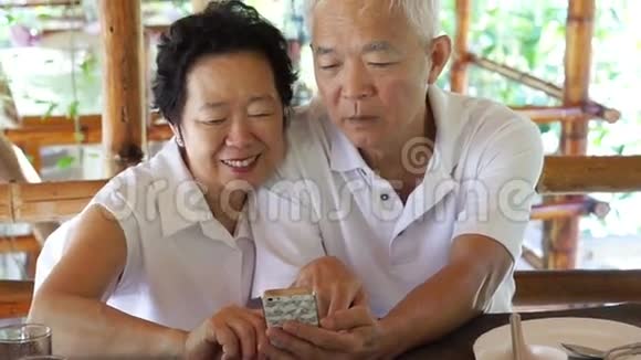 快乐的亚洲老两口看自拍照片手机视频的预览图