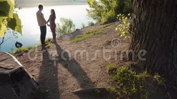 幸福的年轻夫妇在湖边牵手视频的预览图