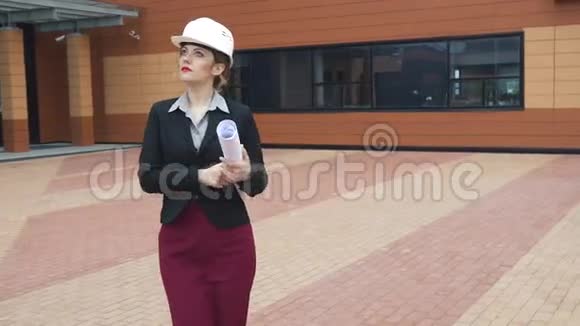 建筑师年轻女子走在一个建筑工地和持有蓝图戴着安全帽的建筑工人女商人在工作视频的预览图