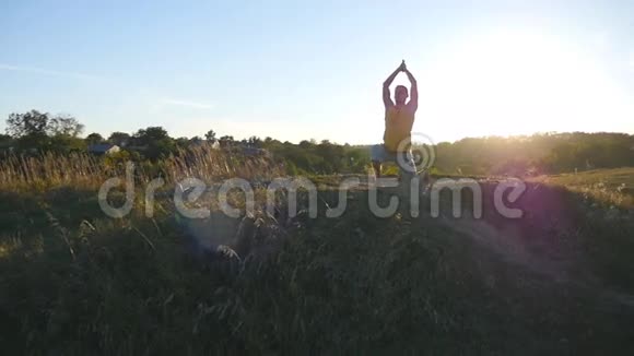 日落时分年轻人在山上练习瑜伽动作和姿势在大自然中站在瑜伽姿势的运动男美丽美丽视频的预览图