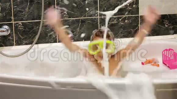 带着潜水面具的小女孩在带泡沫的浴缸里玩耍视频的预览图