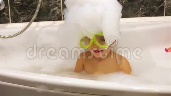 带着潜水面具的小女孩在带泡沫的浴缸里玩耍视频的预览图