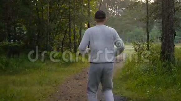 戴着棒球帽的年轻运动员穿过树林视频的预览图