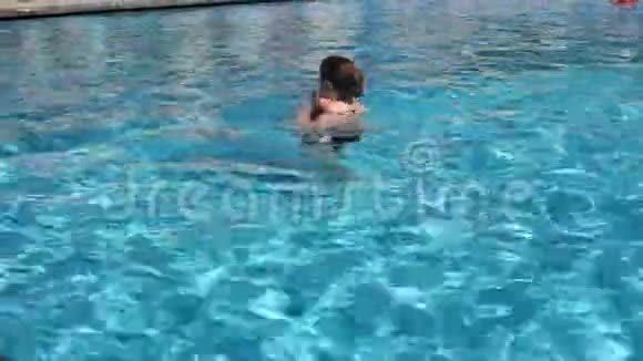一个女人和她的小儿子在游泳池里游泳泳池里的暑假视频的预览图