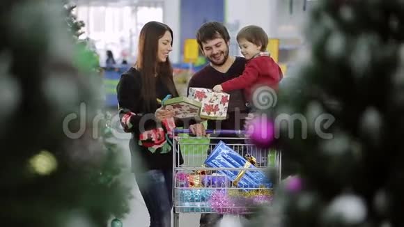 美丽的一家人正在超市买圣诞礼物妈妈带着儿子圣诞球男孩微笑视频的预览图