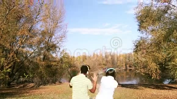 男人和女人坐在湖边用耳机听音乐视频的预览图