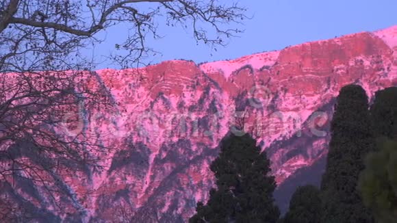雪中的群山在黎明时被太阳照亮视频的预览图