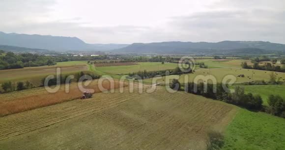 玉米收获与联合收割机和拖拉机在田间的空中镜头视频的预览图