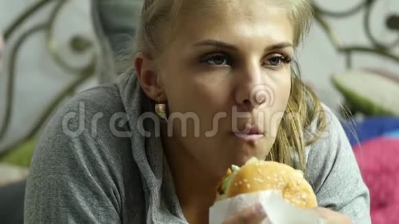 满意的女人在她房间的床上吃快餐汉堡很垃圾的食物慢动作视频的预览图