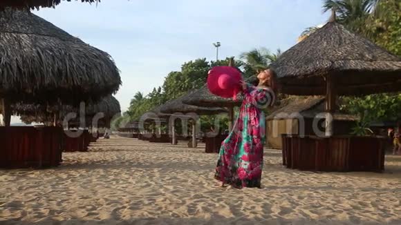 穿着长裙的女孩在海滩上打着雨伞摆姿势视频的预览图