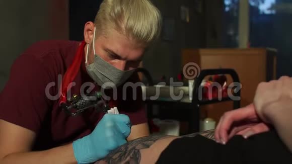 一个纹身艺术家在沙龙里给一个女孩的腿做纹身的特写视频的预览图