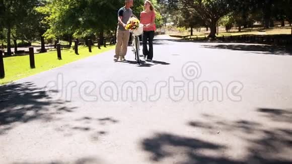 快乐的一对夫妇骑着自行车和一束鲜花散步视频的预览图