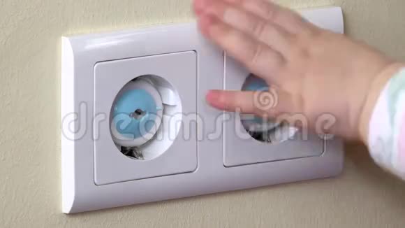 婴儿手伸出装有蓝色安全插头的电源插座视频的预览图