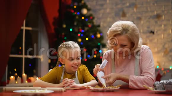 快乐的奶奶和女孩为圣诞派对装饰饼干节日快乐视频的预览图