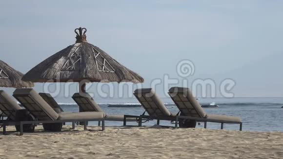在热带度假胜地设有躺椅和遮阳棚的沙滩巴厘岛印度尼西亚视频的预览图