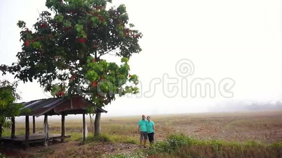 视频亚洲资深夫妇站在凉亭旁边中间雾蒙蒙的稻田农业和农业企业视频的预览图
