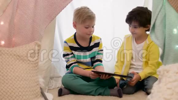 带平板电脑的小男孩在家里的儿童帐篷里视频的预览图