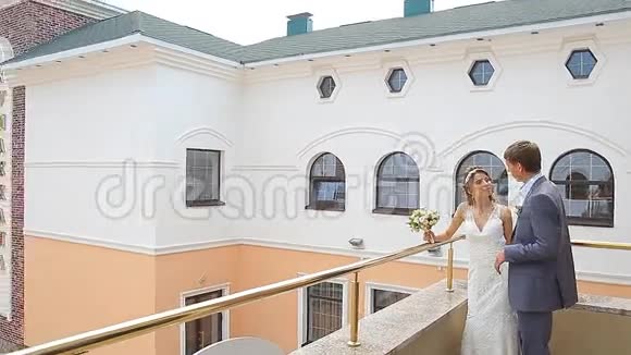 漂亮的年轻夫妇站在阳台上视频的预览图