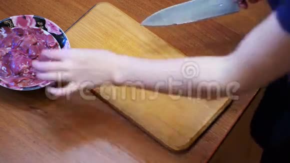 女厨师在家庭厨房的木制厨房板上切鸡肝肉视频的预览图