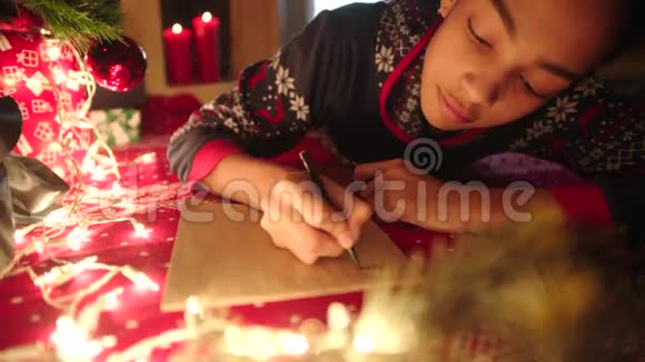 少女躺在装饰好的圣诞树旁给圣诞老人写信视频的预览图