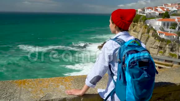背着背包的女人可以欣赏到葡萄牙玛尔附近的海洋海岸视频的预览图