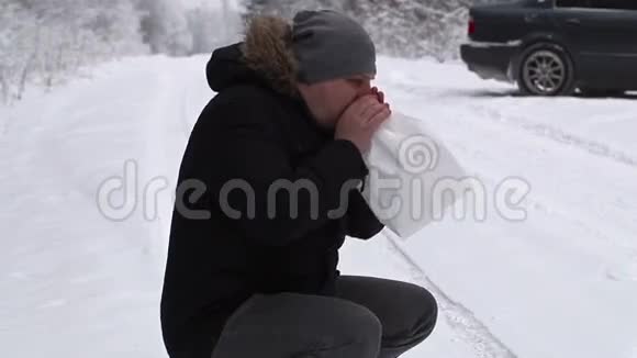 在下雪的路上压力很大的人在靠近汽车的纸袋里呼吸视频的预览图