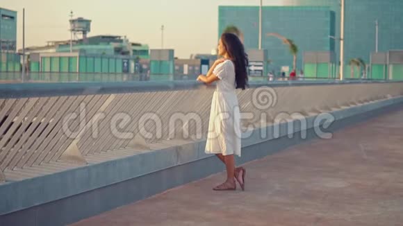 穿着白色裙子的女孩站在海滨长廊露台上视频的预览图