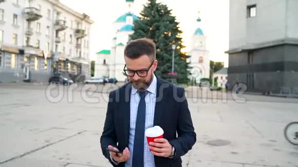 男人用智能手机说话喝着咖啡走在街上视频的预览图