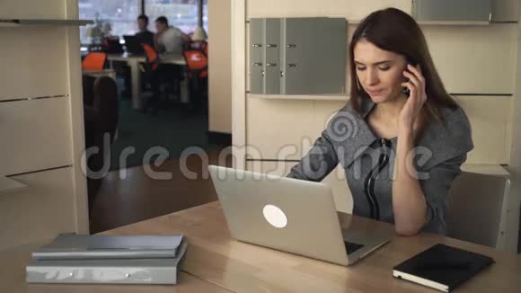 女商人在分开的办公室里用手提电脑和手机聊天视频的预览图