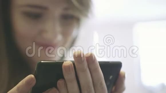年轻微笑的女人手里拿着智能手机在互联网上冲浪视频的预览图