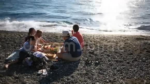 和孩子们在海滩上吃披萨的朋友海边野餐视频的预览图