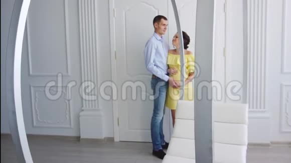 穿着黄色裙子的怀孕女孩和丈夫在室内视频的预览图