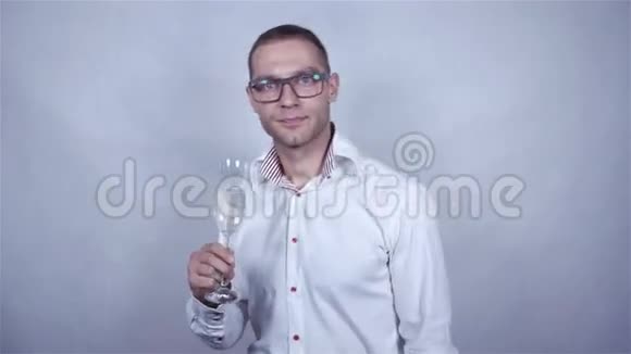 英俊的男人在灰色背景上用一杯香槟庆祝视频的预览图