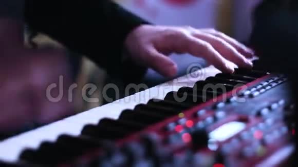 音乐表演者手在电子键盘上演奏的特写画面和控制台上转动旋钮视频的预览图