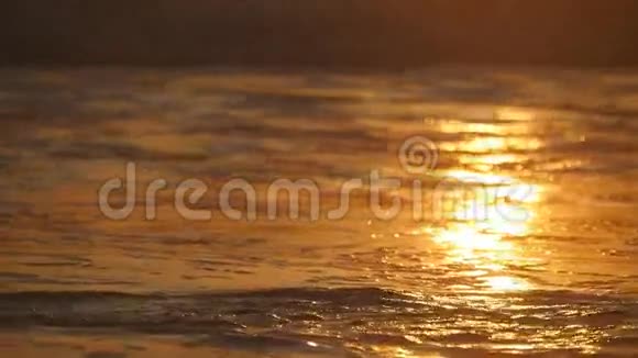 日落时美丽的金色海浪橙色的日出反射在海水上波浪在大风上溅起的浪潮视频的预览图