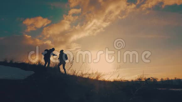 两个徒步旅行在山上互相帮助团队合作情侣徒步旅行互相帮助信任帮助日落视频的预览图