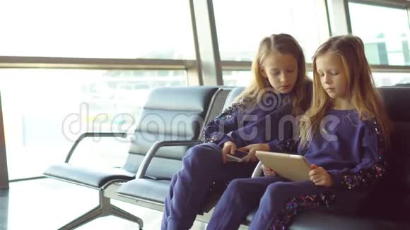 在机场等待登机和玩手提电脑的可爱小女孩视频的预览图