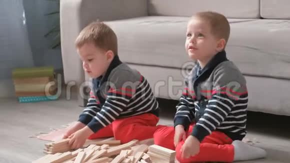 双胞胎兄弟正在用坐在他们房间沙发旁的木头积木搭建视频的预览图