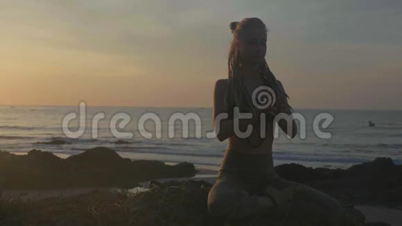日落时剪影瑜伽练习勇女在沙滩上做瑜伽运动视频的预览图