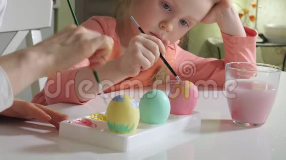 母亲和女儿用彩色颜料画复活节彩蛋视频的预览图