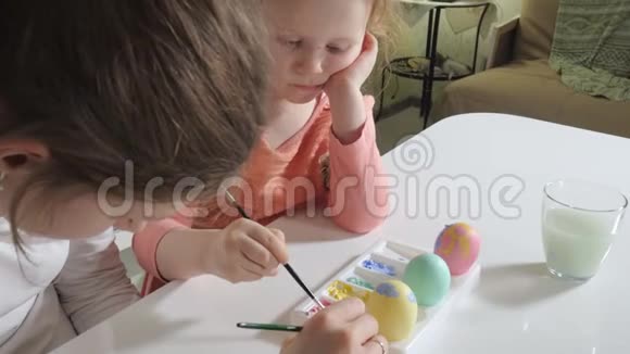 母亲和女儿用彩色颜料画复活节彩蛋视频的预览图