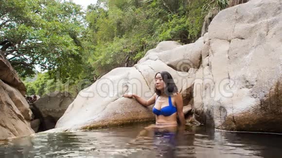 女孩坐在山涧造就的小湖里洗澡视频的预览图