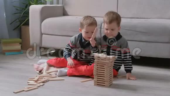 双胞胎兄弟正在用坐在他们房间里沙发旁的木块建造一座塔视频的预览图