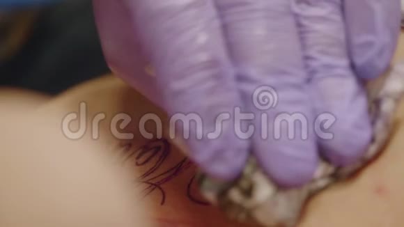 纹身艺术家的手戴着硅手套纹身女孩在工作室慢镜头视频的预览图