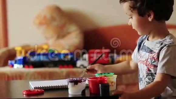 可爱的男孩在桌子上画画视频的预览图