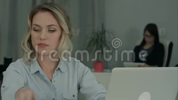 微笑的年轻女子坐在办公桌上用手机说话视频的预览图